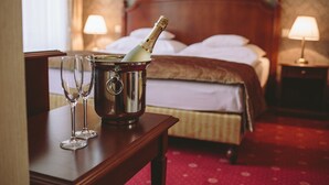 A hotel room with a wooden bed, two bedside lamps, a red carpet, and a bottle of champagne in a metal bucket. - Mozart Hotel (Szeged)