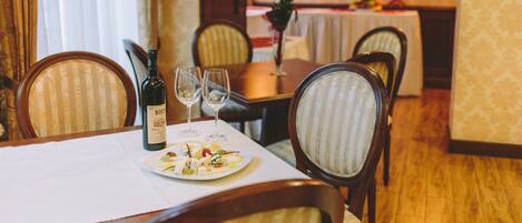 A dining table set with a bottle of wine, glasses, and a plate of appetizers.