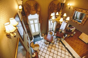 A hotel lobby with a checkered floor, a dining area with a table and chairs, and a chandelier. - Mozart Hotel (Szeged)