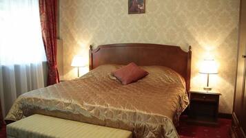 A neatly made bed with a quilted headboard, a single pillow, and a bedside table with a lamp.