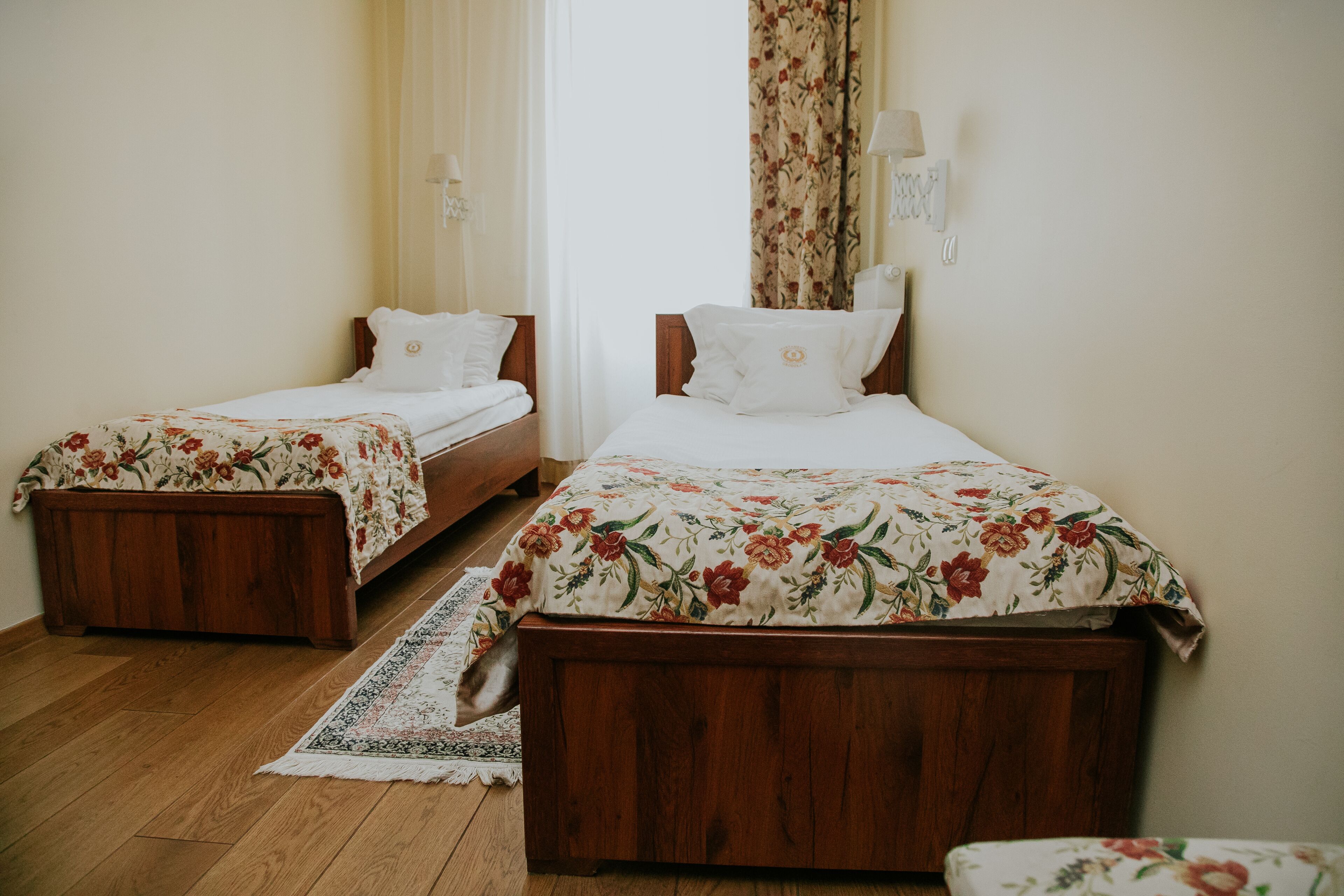 A room with two wooden beds, each with floral bedding and white pillows.