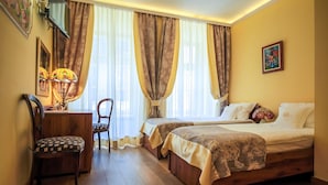 A bedroom with two beds, a wooden desk, a chair, and a lamp. - Aparthotel Grodzka 21 (Kraków)