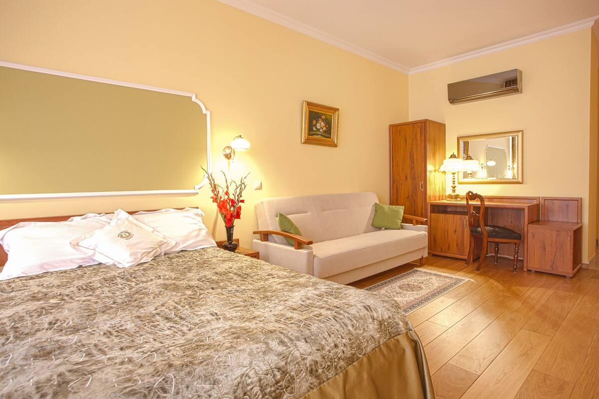 Een hotelkamer met een bed, een slaapbank, een bureau en een stoel.