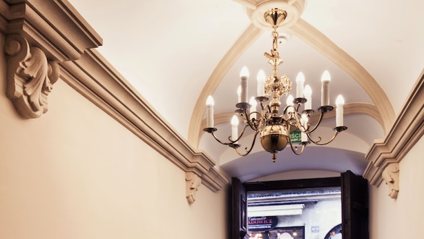 A hallway with a chandelier, a door leading to a public area, and a tiled floor. - Aparthotel Grodzka 21 (Kraków)