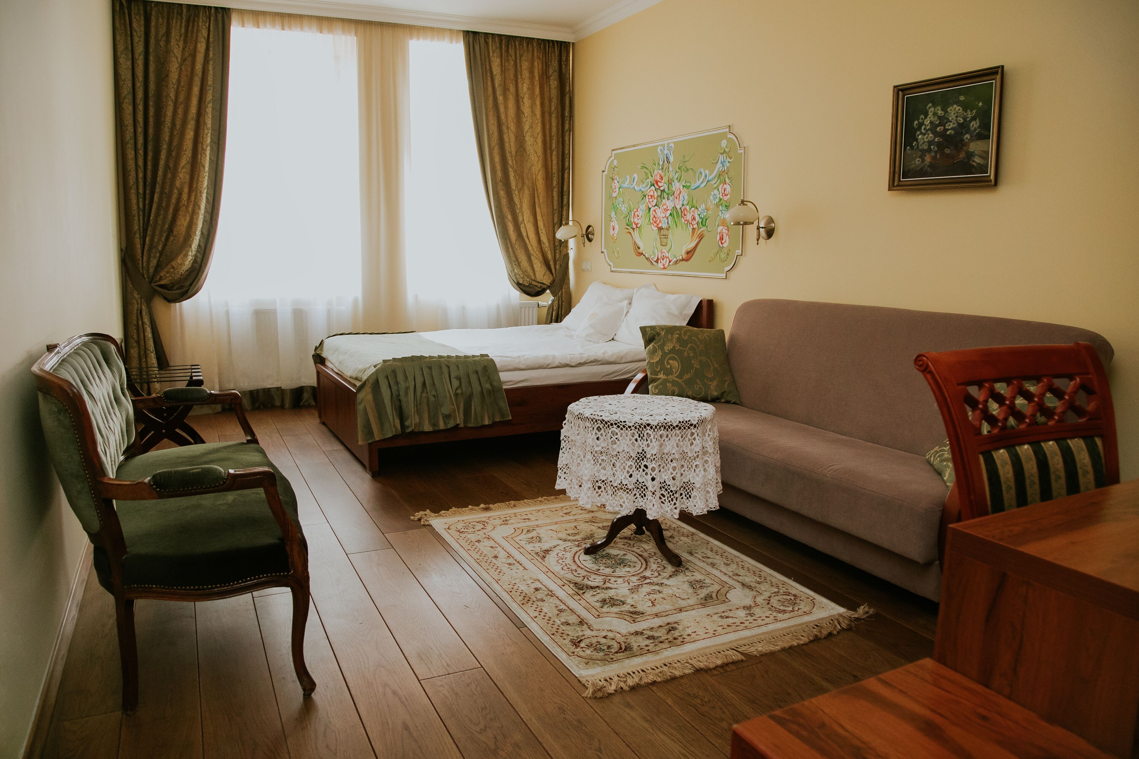 Una habitación con una cama, un sofá, una silla, una mesita y un adorno en la pared.
