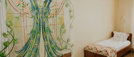 Une chambre à coucher avec un lit, une couvre-lit à motifs floraux et une fresque représentant un paon sur le mur.