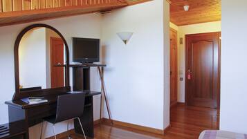 A room with a wooden desk, chair, television, and a mirror.