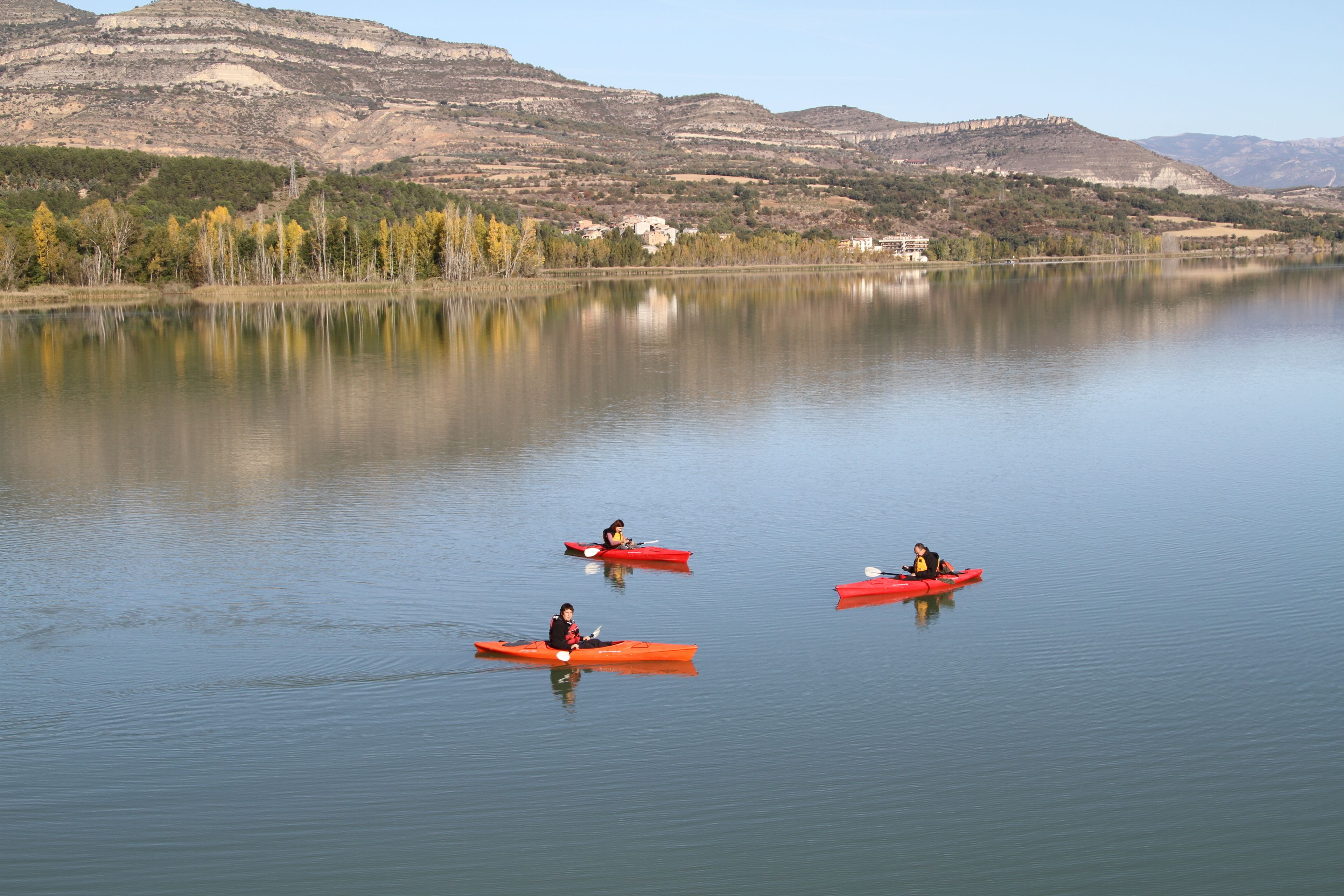 A calm lake with kayaks and a mountainous backdrop.