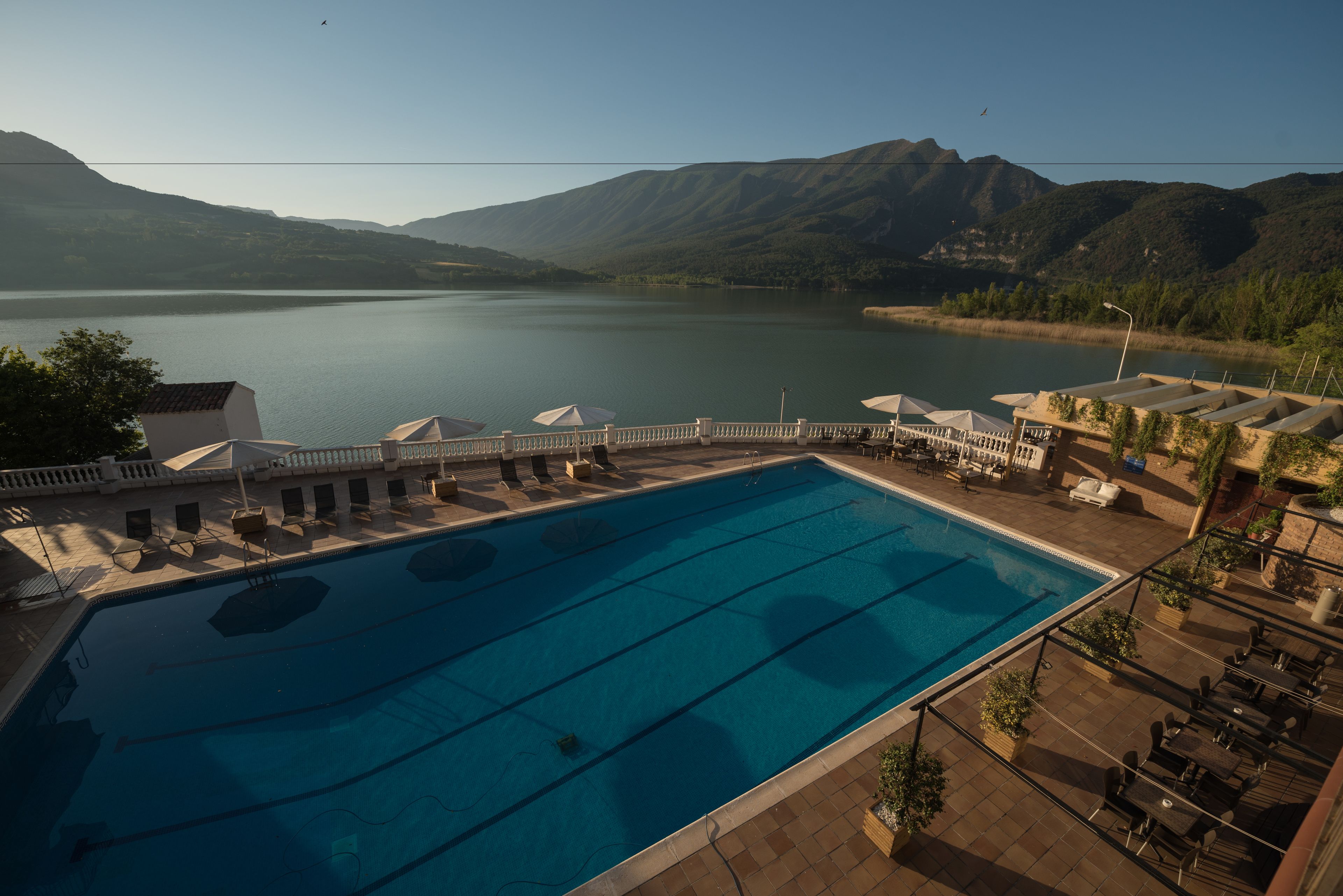 A swimming pool with a view of mountains and a lake.