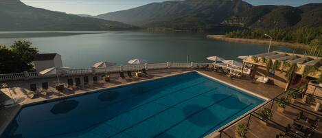 A swimming pool with a view of mountains and a lake.