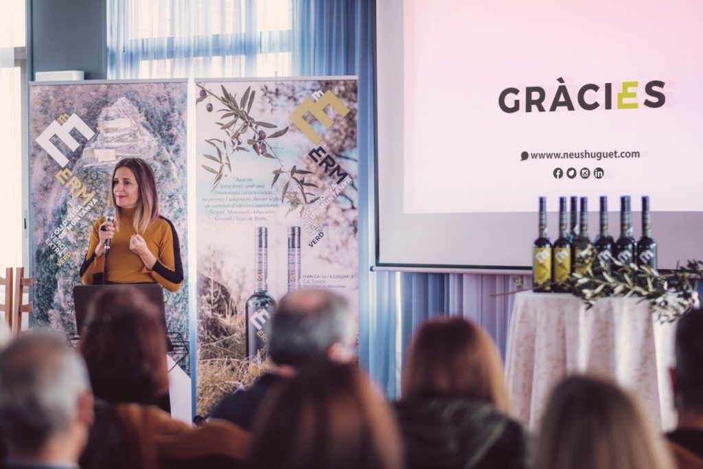 A person giving a presentation at a conference with a backdrop featuring a logo and text.