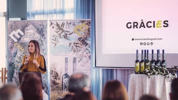 A person giving a presentation at a conference with a backdrop featuring a logo and text.