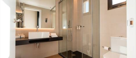 A modern bathroom with a glass-enclosed shower, a white sink, and a toilet.