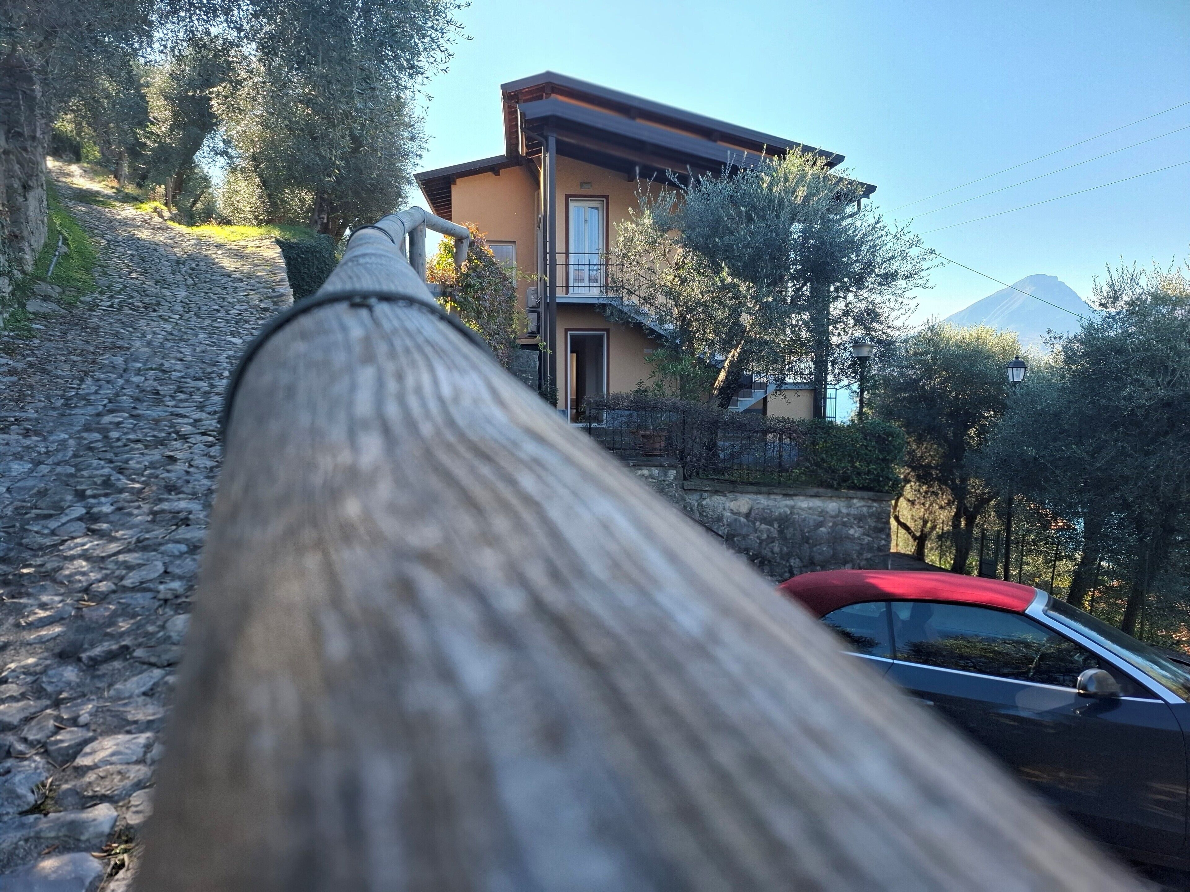 Un sendero de piedra que lleva a una casa, con un coche rojo estacionado cerca.