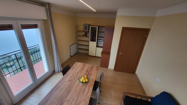 Un comedor con una mesa y sillas de madera, un cuenco de limones y vistas a un balcón con barandilla.