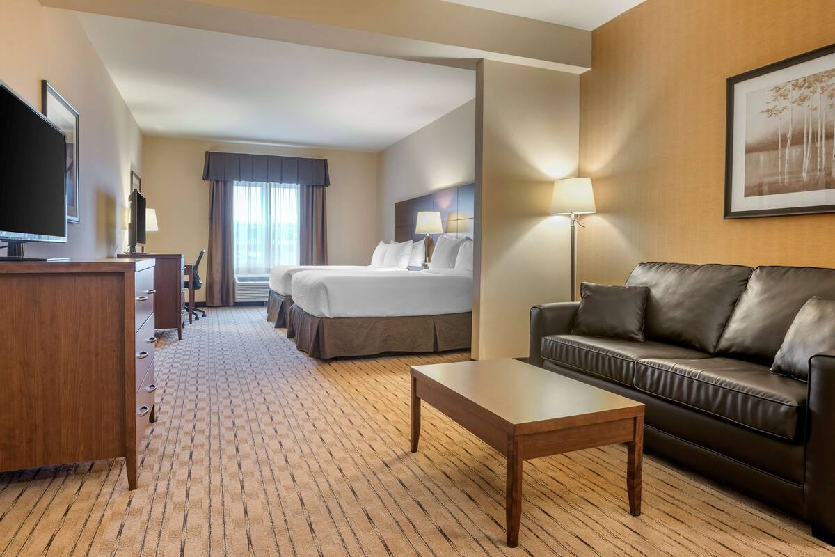 A hotel room with a bed, a desk, a coffee table, a sofa, and a TV.