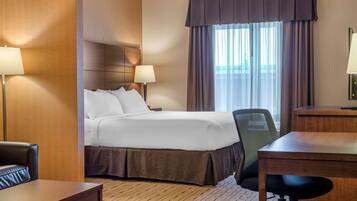 A hotel room with a bed, a desk, a chair, and a window with curtains.