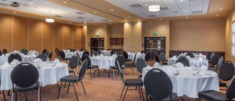 A conference room with multiple round tables, each set with chairs and tableware.