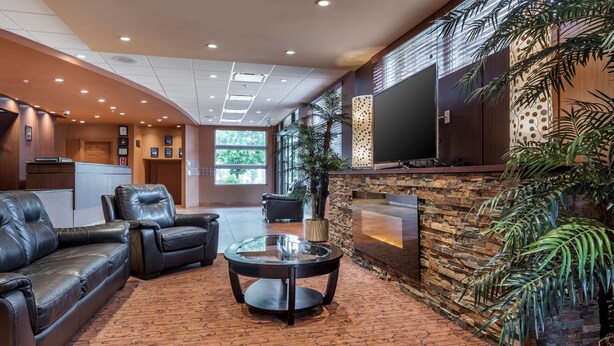 A lobby with leather sofas, a glass coffee table, a stone fireplace, and a large flat-screen TV. - Best Western Plus Bathurst Hotel & Suites (Bathurst)