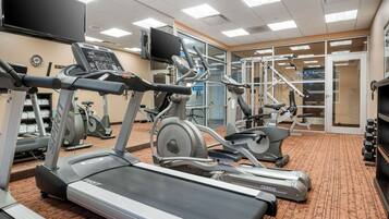 Een fitnessruimte met loopbanden, hometrainers en krachtapparaten.