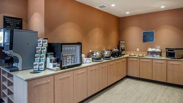 Un área de desayuno con una cafetera, un refrigerador y una variedad de alimentos.