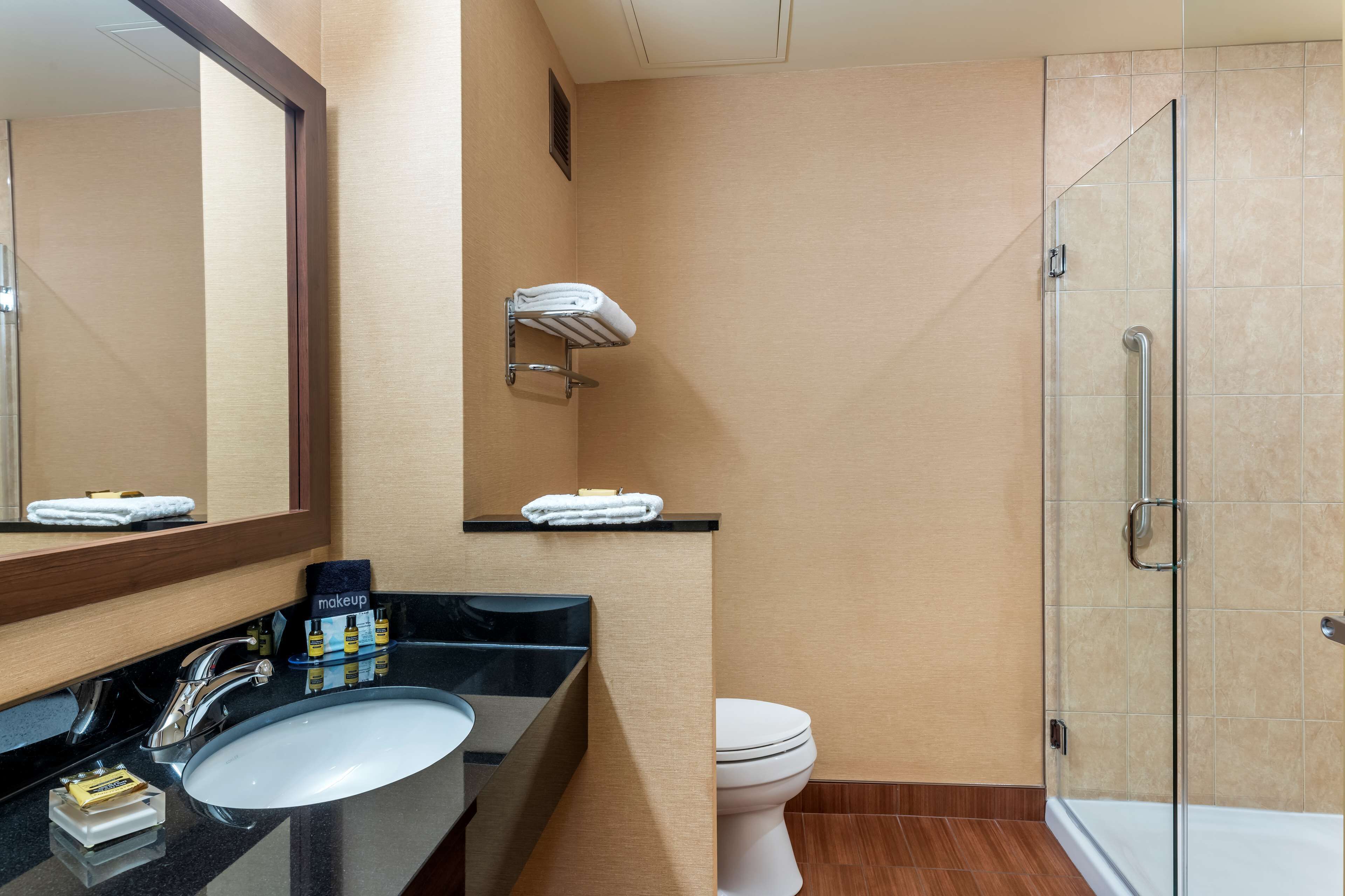 A bathroom with a sink, mirror, towel rack, and shower.