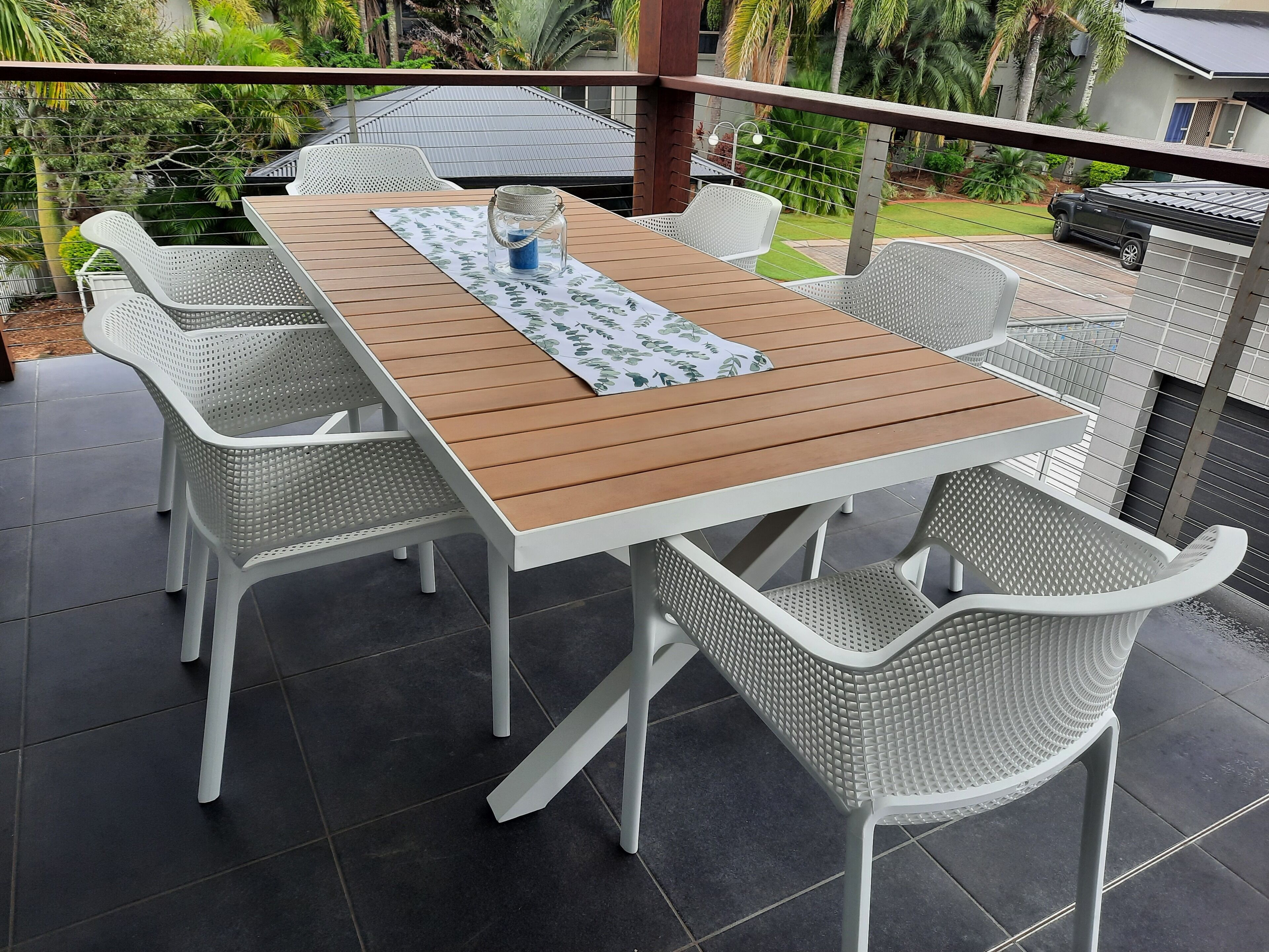 An outdoor patio with a wooden table and white wicker chairs.