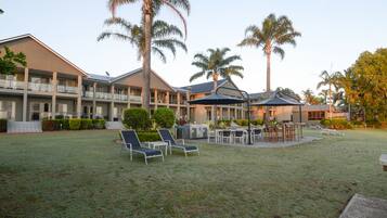 Un hotel con diversi piani, zone relax all'aperto e palme.
