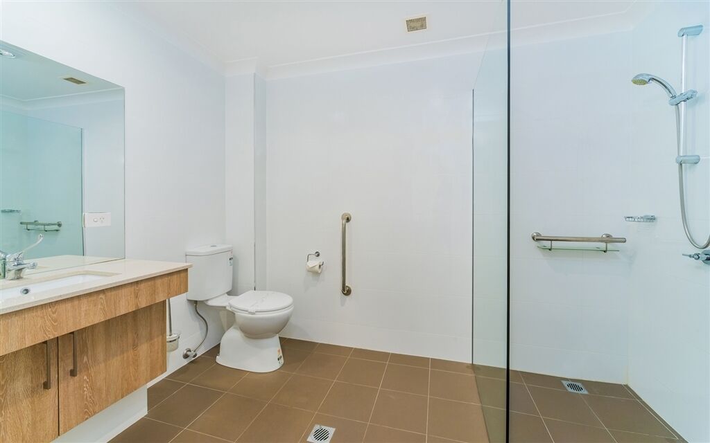 Un baño con inodoro, lavamanos, espejo y cabina de ducha de vidrio.
