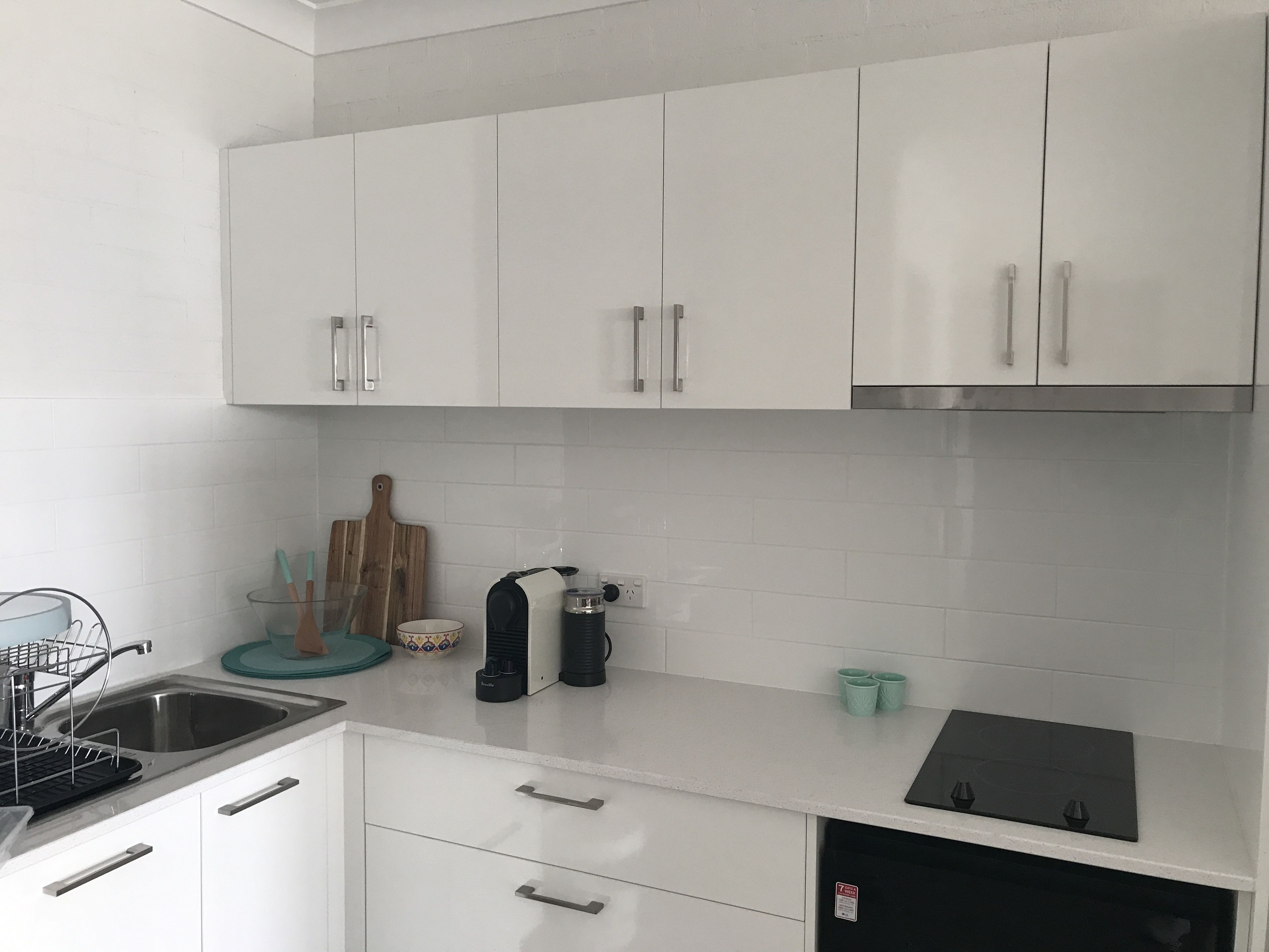 A modern kitchen with white cabinets, a stainless steel sink, and a black stove.