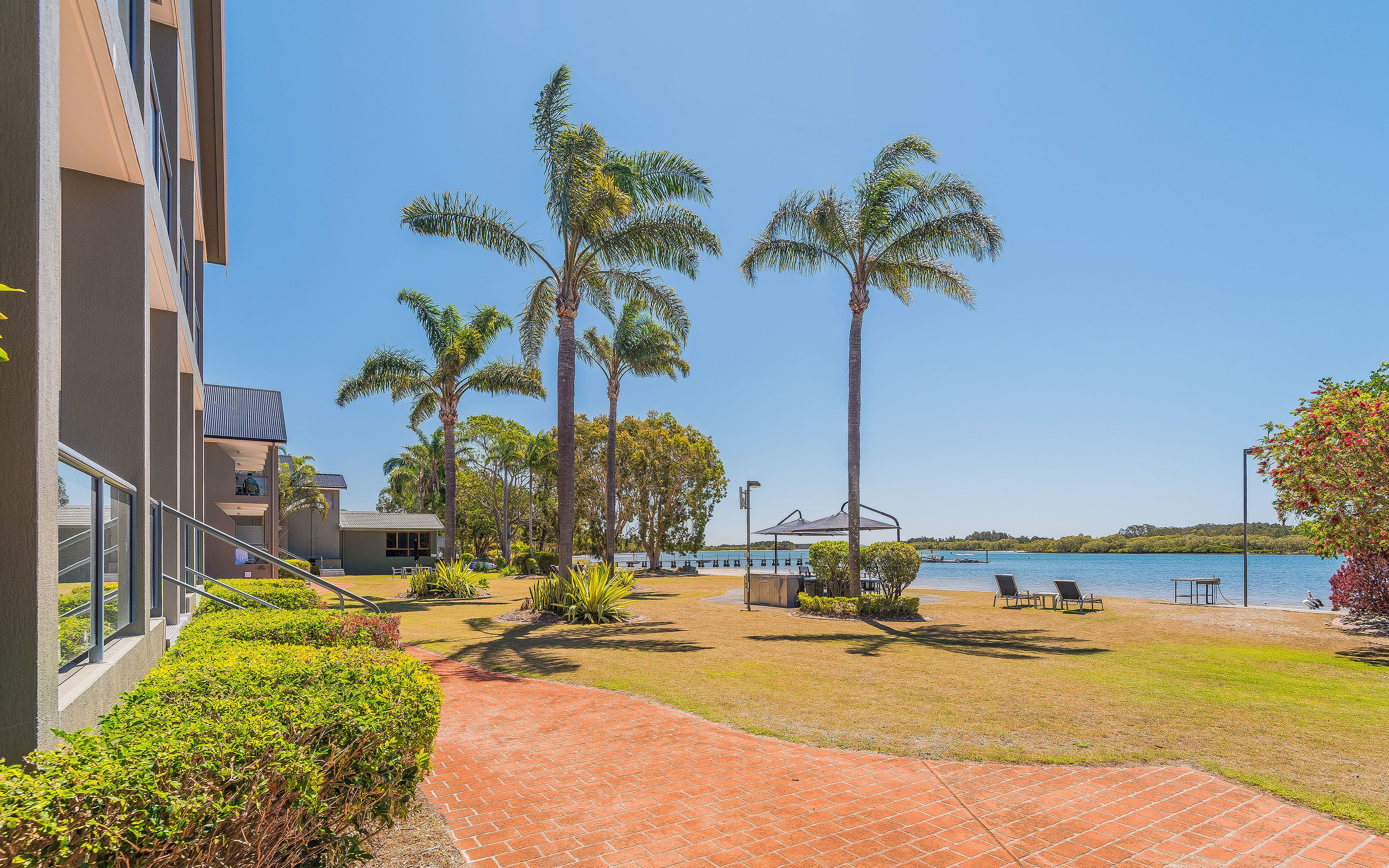 Un resort con zona de piscina, palmeras y vistas al agua.