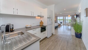 A modern kitchen with white cabinets, a stainless steel sink, and a built-in oven. - Moby Dick Waterfront Resort Motel (Yamba)