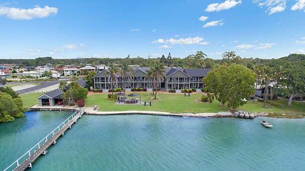A waterfront hotel with a dock, a pool area, and a large building with multiple floors. - Moby Dick Waterfront Resort Motel (Yamba)