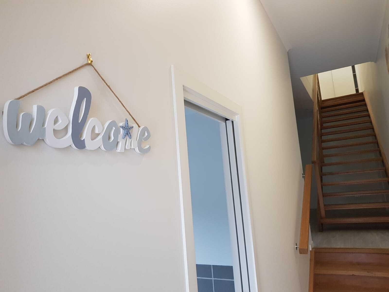 A staircase leading to a landing with a 'Welcome' sign above a door.