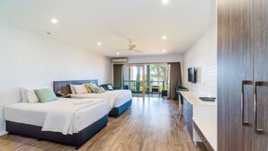 A modern hotel room with two beds, a flat-screen TV, a desk, and a balcony with a view. - Moby Dick Waterfront Resort Motel (Yamba)