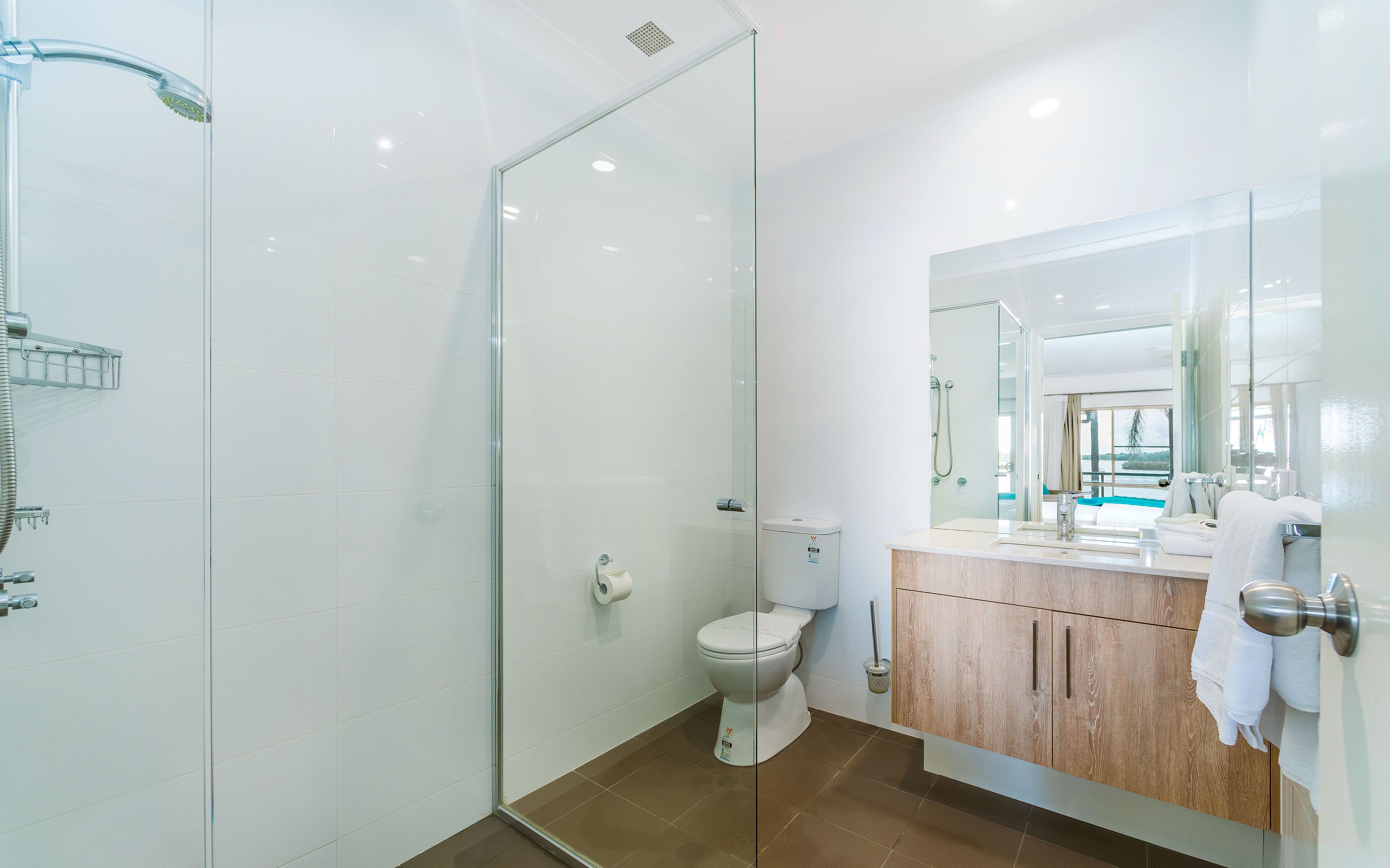 Un baño moderno con cabina de ducha de vidrio, inodoro y tocador con espejo.
