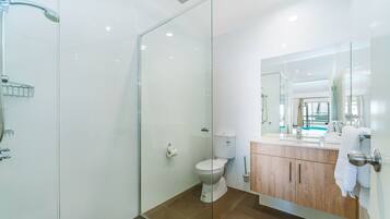 Un baño moderno con cabina de ducha de vidrio, inodoro y tocador con espejo.