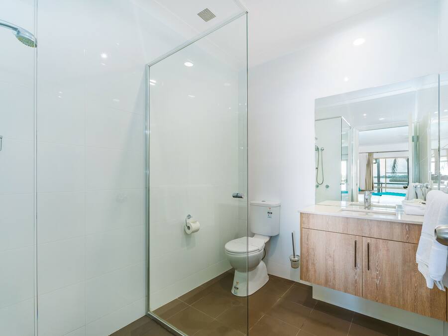 Un baño moderno con cabina de ducha de vidrio, inodoro y tocador con espejo.