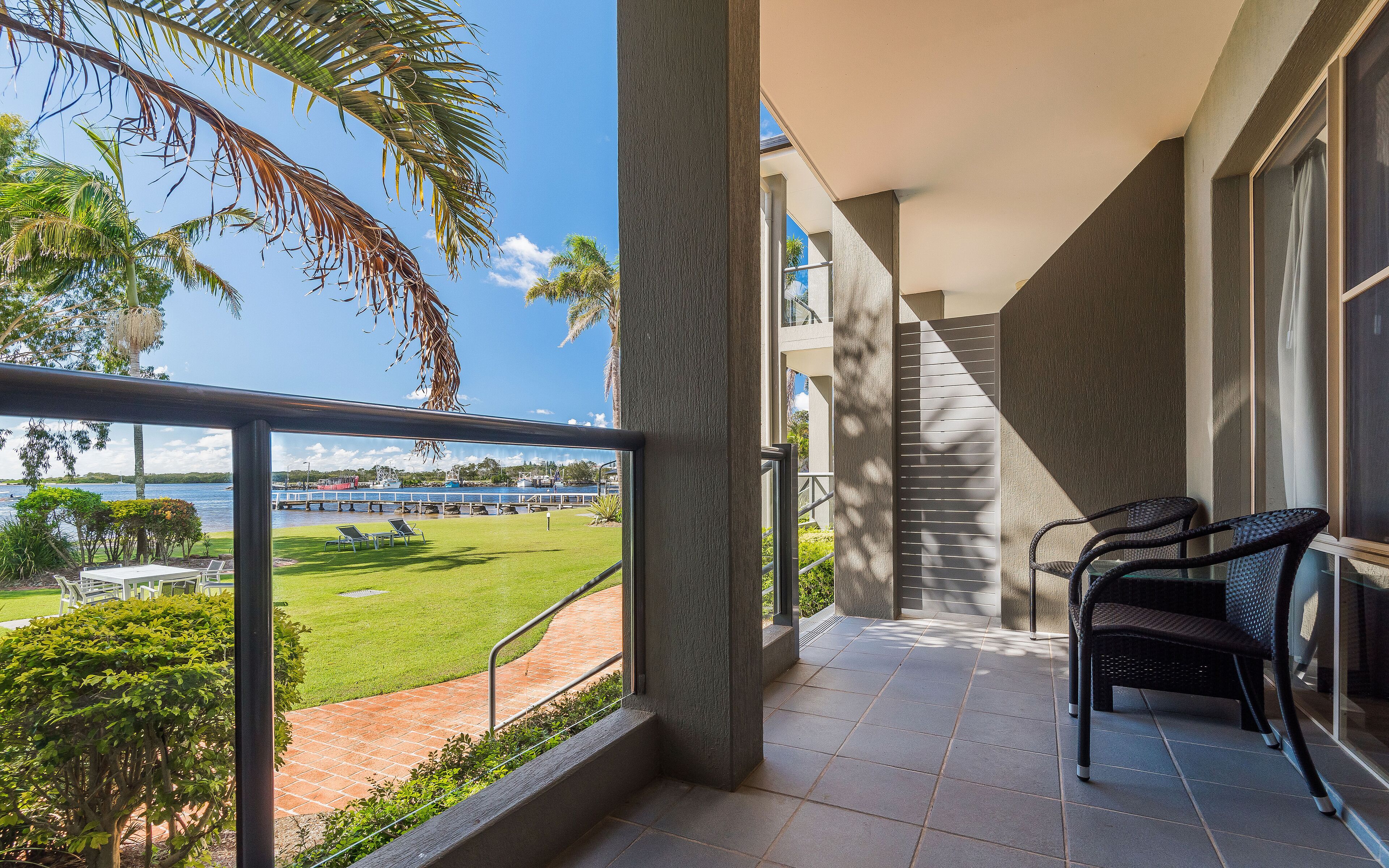 Een balkon met uitzicht op een meer, buitenmeubilair en een trap naar een hoger gelegen niveau.