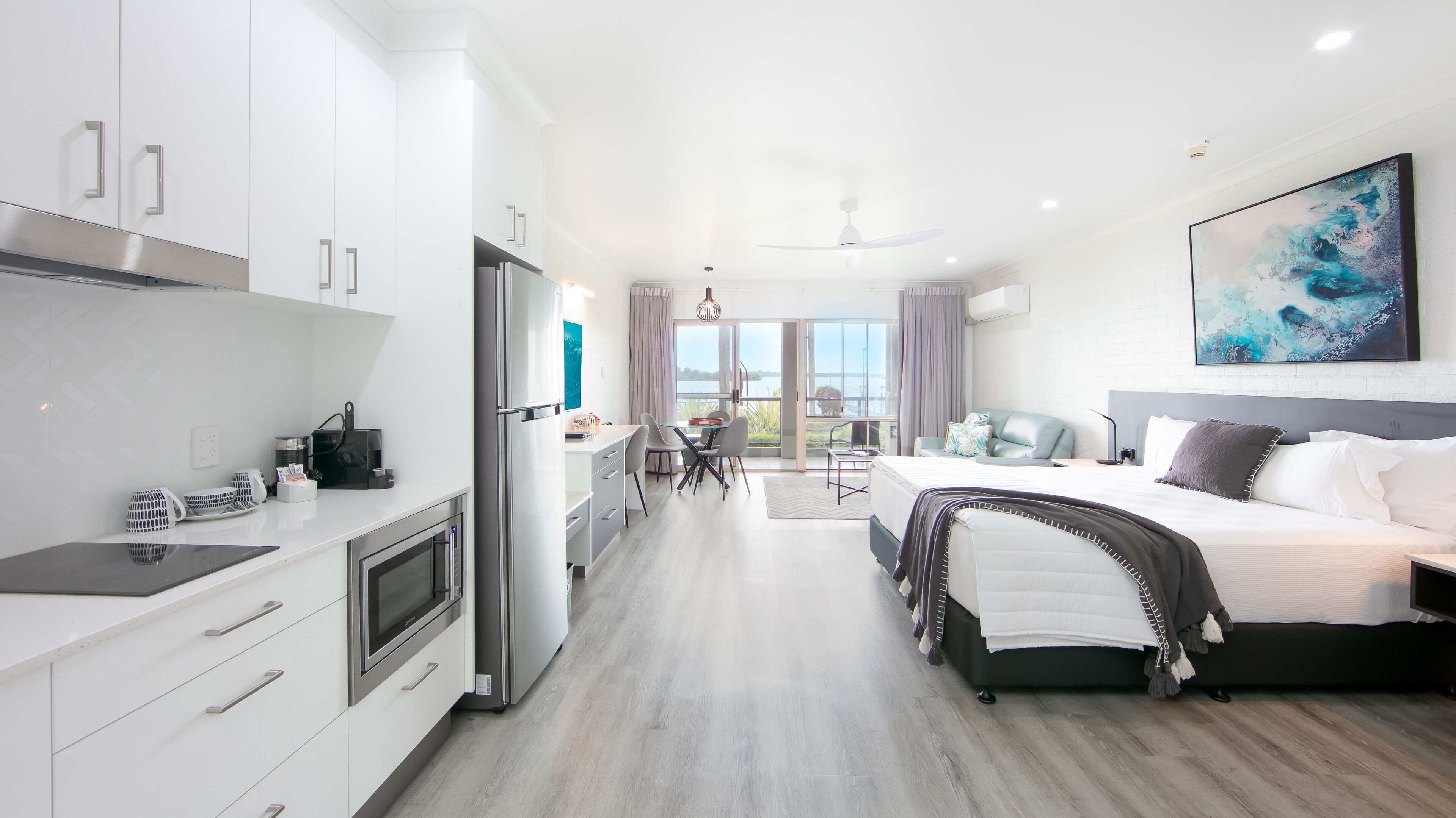 Une chambre d’hôtel moderne dotée d’une cuisine, d’un coin repas et d’un grand lit.