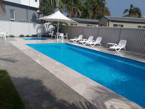 Una piscina al aire libre, sillones reclinables de piscina
