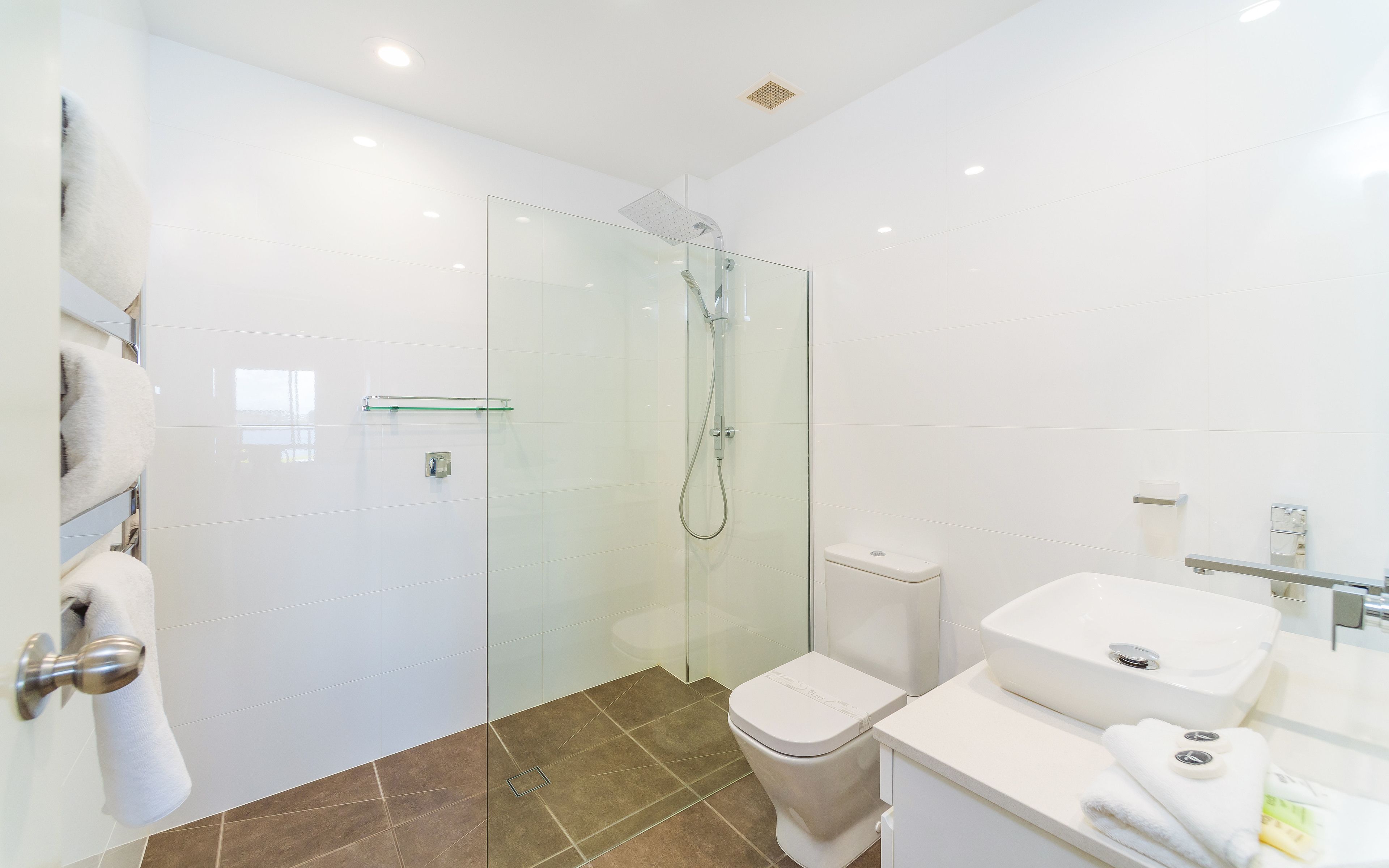 Een moderne badkamer met een douchecabine van glas, een wit toilet en een wastafel met spiegel.