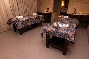 Two beds with 'AKASA LUXE' signs, a wooden bench, a mirror, and a stone wall. - Hilton Jaipur (Jaipur)