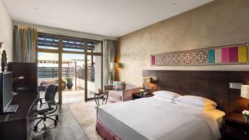 A hotel room with a bed, desk, chair, and a view of the outdoors.