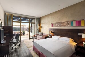 A hotel room with a bed, desk, chair, and a view of the outdoors. - Hilton Jaipur (Jaipur)