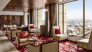 A modern hotel room with a large window, seating area, and a city view. - Hilton Jaipur (Jaipur)