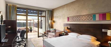 Habitación de hotel con cama, escritorio, silla y vista al exterior.