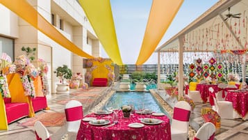Een balzaal met gedekte tafels voor een formeel evenement, een centrale fontein en decoratieve elementen.