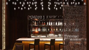 A bar area with hanging spherical light fixtures, a bar counter, and seating. - Hilton Jaipur (Jaipur)
