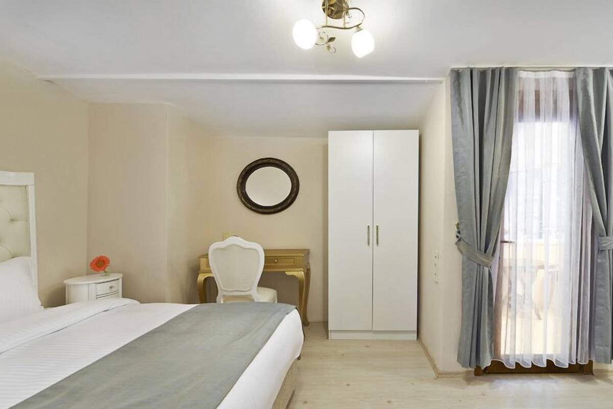 A bedroom with a bed, a desk, a wardrobe, and a mirror.